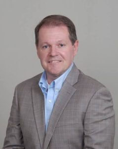 Photo of a man from the chest up looking at the camera.
