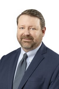 Photo of a man from the chest up looking at the camera.